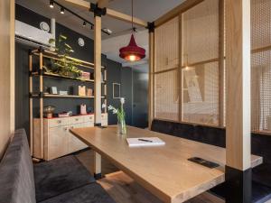 a dining room with a wooden table and a couch at Oru Hub Hotel Tallinn - Handwritten Collection in Tallinn