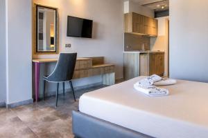 a bedroom with a bed and a desk and a chair at Tridente Mare Apart Hotel in Pefkochori