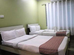 a hotel room with two beds and a window at Brichyalaya Kohalpur in Kohalpur