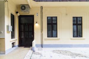 a building with a black door and two windows at Authentic Klauzal Apartment in Budapest