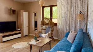 a living room with a blue couch and a tv at Rosa Apartamenty in Dąbki