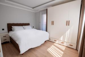 a bedroom with a white bed and a large window at Royal Batın Apart Otel in Trabzon