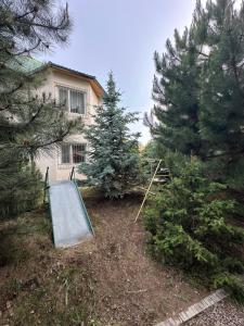 a house with trees and a ramp in the yard at Гостевой дом Достук in Bosteri +6 photos