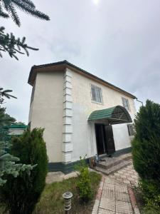 a small white house with a green awning at Гостевой дом Достук in Bosteri