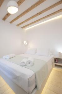 a white bedroom with two beds with towels on it at Ethereal House - Seafront by Cheronissos Beach in Cherronisos