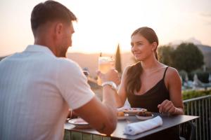 a man and a woman sitting at a table with a drink at Hotel Boffenigo - The Golden Hour in Costermano