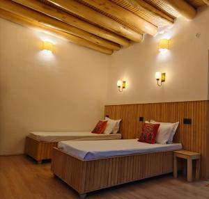 two beds in a room with wooden walls at Faryok Resort in Nūrla