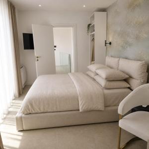 a white bedroom with a large bed and a chair at White Hills Villa in Zadar +28 photos