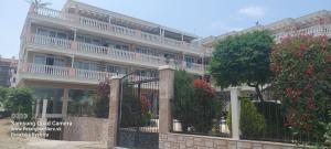 a building with a fence and a tree in front of it at Apartman RS 27 Апартамент на плажа с вълшебна гледка към морето, напълно оборудвана кухня и безплатен паркинг, със самостоятелен басейн, балкон и асансьор Самостоятелен душ и тоалетна ТОП местоположение in Lozenets