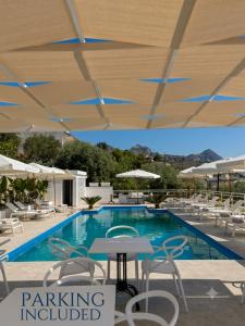 a swimming pool with chairs and a table and an umbrella at IG - "Villa Don Antonio" Apartments in Giardini Naxos