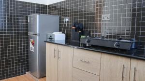 a kitchen with a black tiled wall with a refrigerator at AC one bedroom apartment , 5 min walk from bofa road, baobab resort ,Canna Lily in Kilifi