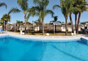 a large blue swimming pool with palm trees at Villa Selinus 6598 in Castelvetrano Selinunte