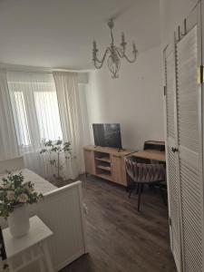 a living room with a television and a desk with a chair at Apartament Jaroty dla 4 osób in Olsztyn
