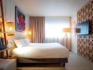 a hotel room with a bed and a television at Mercure Saint Raphael Centre Plage in Saint-Raphaël