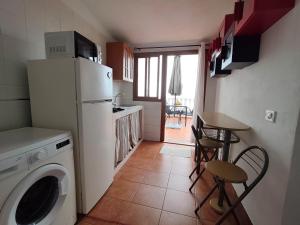 a kitchen with a washing machine and a table with chairs at Estudio Mary Espectaculares Vistas al Mar in Los Llanillos