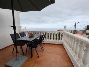 a balcony with a table and chairs and an umbrella at Estudio Mary Espectaculares Vistas al Mar in Los Llanillos +3 photos