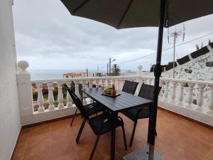 a table with chairs and an umbrella on a balcony at Estudio Mary Espectaculares Vistas al Mar in Los Llanillos