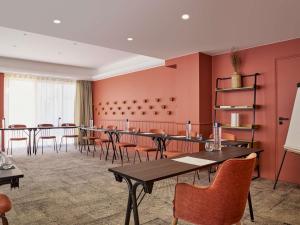 a room with tables and chairs in a room with pink walls at Mercure Saint Raphael Centre Plage in Saint-Raphaël