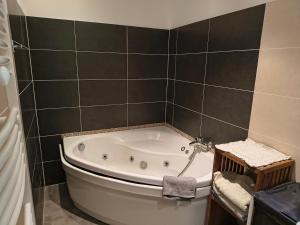 a bath tub in a bathroom with black tiles at Chambre privative in Lecci +11 photos
