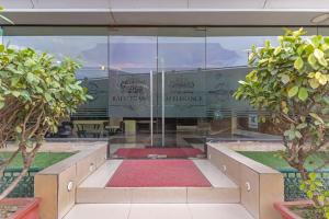 a building with a glass wall with trees in front at Treebo Premium Raj Elegance Manyata Tech Park in Bangalore