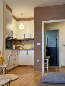 a kitchen with white cabinets and a table at Apartman Ninolić in Jagodina