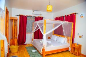 a bedroom with a canopy bed with red curtains at FRAPG camp and lodge in Mikumi
