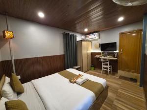 a bedroom with a bed and a desk with a television at Hotel Pohor Regency 10 minutes travel to Kamakhya Temple in Guwahati