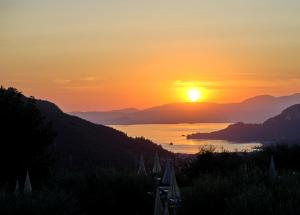 a sunset over a body of water with mountains at Hotel Boffenigo - The Golden Hour in Costermano