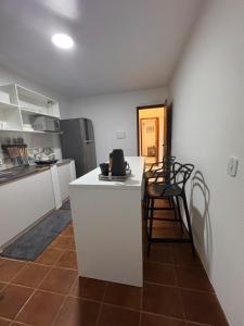 a kitchen with a white counter and chairs in it at Office-Stay in Casimiro de Abreu