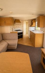a small kitchen with a couch and a stove in a caravan at Rowyhills in Rowy