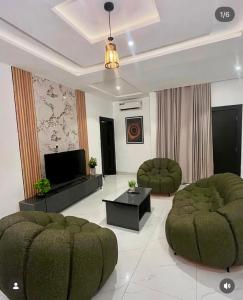 a living room with two green chairs and a television at Homelands in Port Harcourt +6 photos