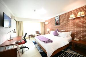 a hotel room with a bed and a brick wall at Aeroport Grand Hotel in Douala