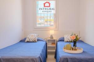 a room with two beds with blue sheets and a window at Casa Norai in Palamós