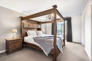 a bedroom with a wooden canopy bed and a window at The Lakeview in Lilydale