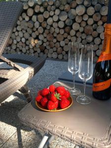 a plate of strawberries on a table with wine glasses at Glamping Hynkov in Příkazy