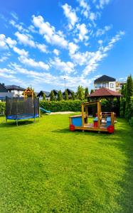 three play structures on a grassy field with a sky at Rowyhills in Rowy