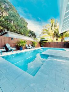 a swimming pool with chairs and a fence at The Miami Grove Oasis in Miami