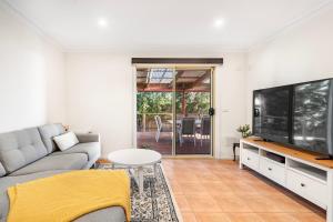 a living room with a couch and a tv at The Lakeview in Lilydale