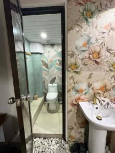 a bathroom with a sink and a toilet with flowers at A.C. Asistin Transient House in Baguio