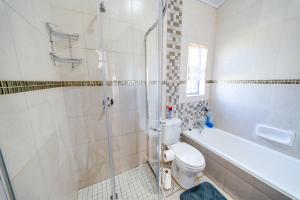 a bathroom with a shower and a toilet and a tub at 22 on Nicol in Secunda +27 photos