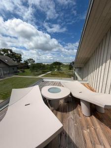 eine Terrasse mit zwei weißen Bänken auf einem Holzdeck in der Unterkunft Skrablas Boutique Hotel in Rucava