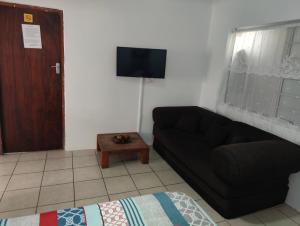 a living room with a black couch and a tv at Hunters Self Catering Apartment in East London