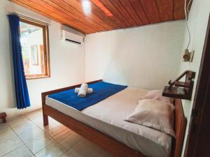 a bedroom with a bed with blue sheets and a window at Likat Surf House in Tua Pejat