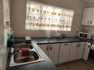 a kitchen with a sink and a microwave at Hunters Self Catering Apartment in East London +6 photos