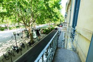 Hôtel Cesar Nîmes Centre Historique & Gare في نيم: شرفة بها شجرة على جانب مبنى