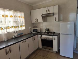 a kitchen with white cabinets and a white refrigerator at Hunters Self Catering Apartment in East London
