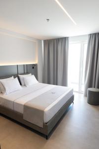 a bedroom with a large bed and a large window at White Amfora Hotel in Shëngjin