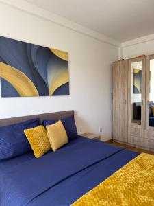 a bedroom with a large blue bed with yellow pillows at Apartman Lambros 2 in Soko Banja