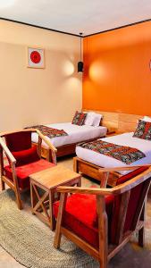 a room with two beds and a chair and a table at Enjipai Ngorongoro Lodge in Karatu