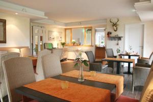a restaurant with tables and chairs and a kitchen at Hotel Landhaus Garni in Fockbek